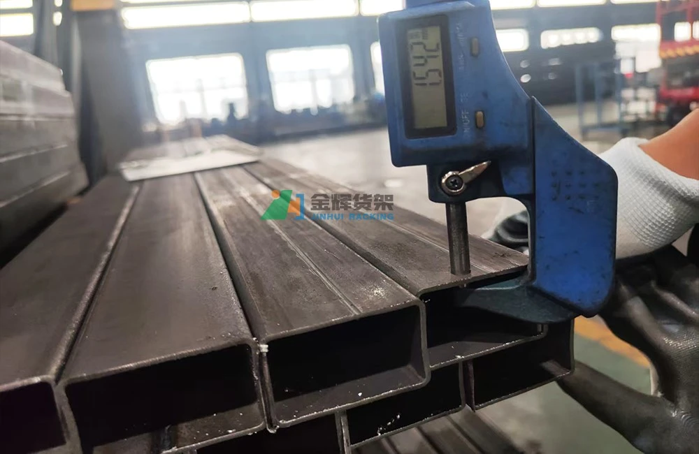 Worker using digital caliper measuring steel racking component for quality control